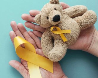 teddy bear with yellow ribbon held in palm of open hands