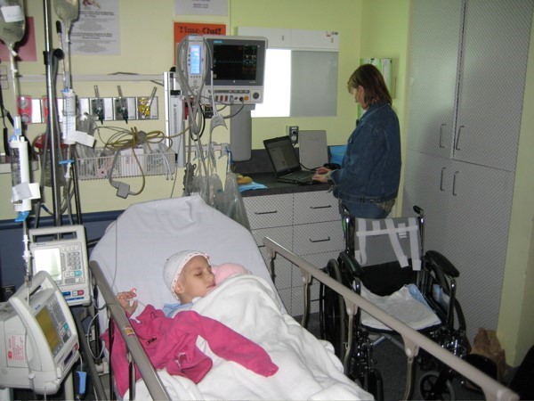 child in hospital bed with adult in the background